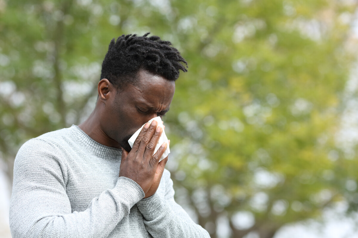 A dandelion's pappus are blowing in the wind. The background is blurred and the sky feels like dusk. Get Spring allergy relief at The Allergy and Asthma Group.